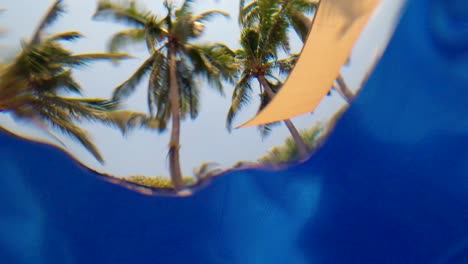 Palm-trees-viewed-from-inside-a-pool-under-the-water-ripples---Slow-Motion