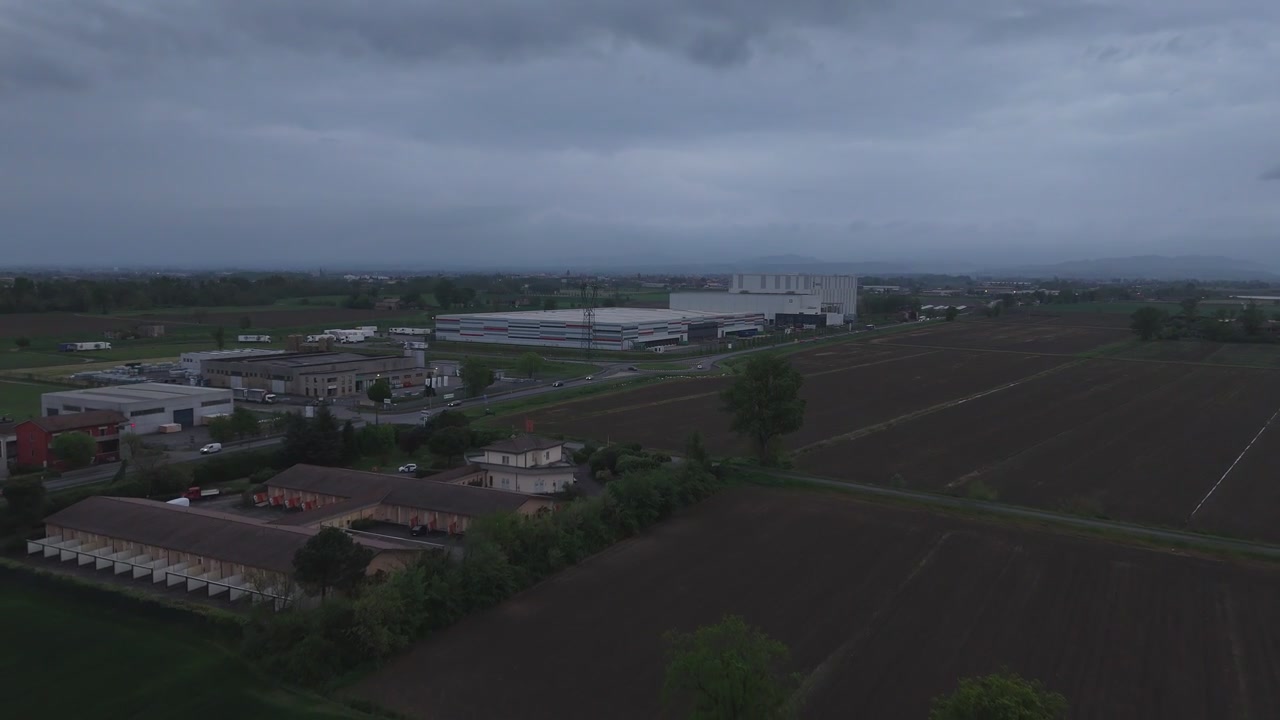 La SS9 Via Emilia Pavese attraversa un paesaggio industriale e agricolo vicino a Fiorenzuola d'Arda, Provincia di Piacenza, Emilia-Romagna, Italia, ripresa aerea con drone vicino all'Autostrada del Sole A1 e all'autostrada A21.