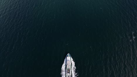 drone overtaking charter tourist boat in birdseye perspective - aerial above boat cruising the fjords of norway