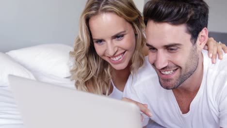 pareja linda mirando la computadora portátil en la cama