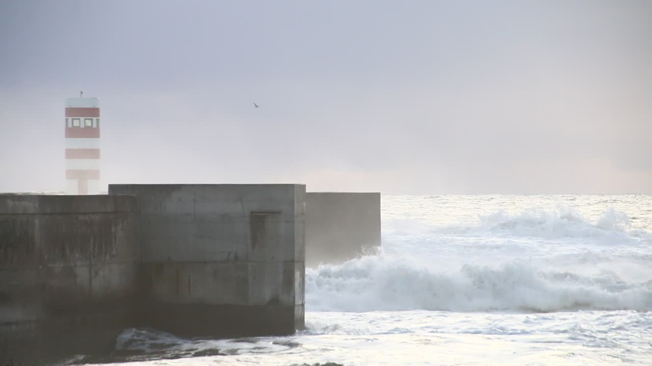 Waves crushing lighthouse in Porto in a cold cloudy and windy evening