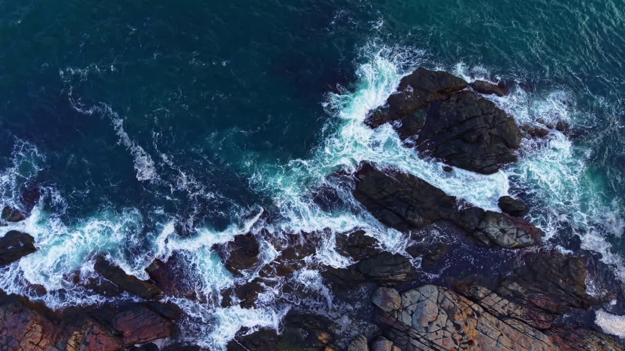 Vista mozzafiato delle onde oceaniche che si infrangono sulle frastagliate rocce costiere al tramonto