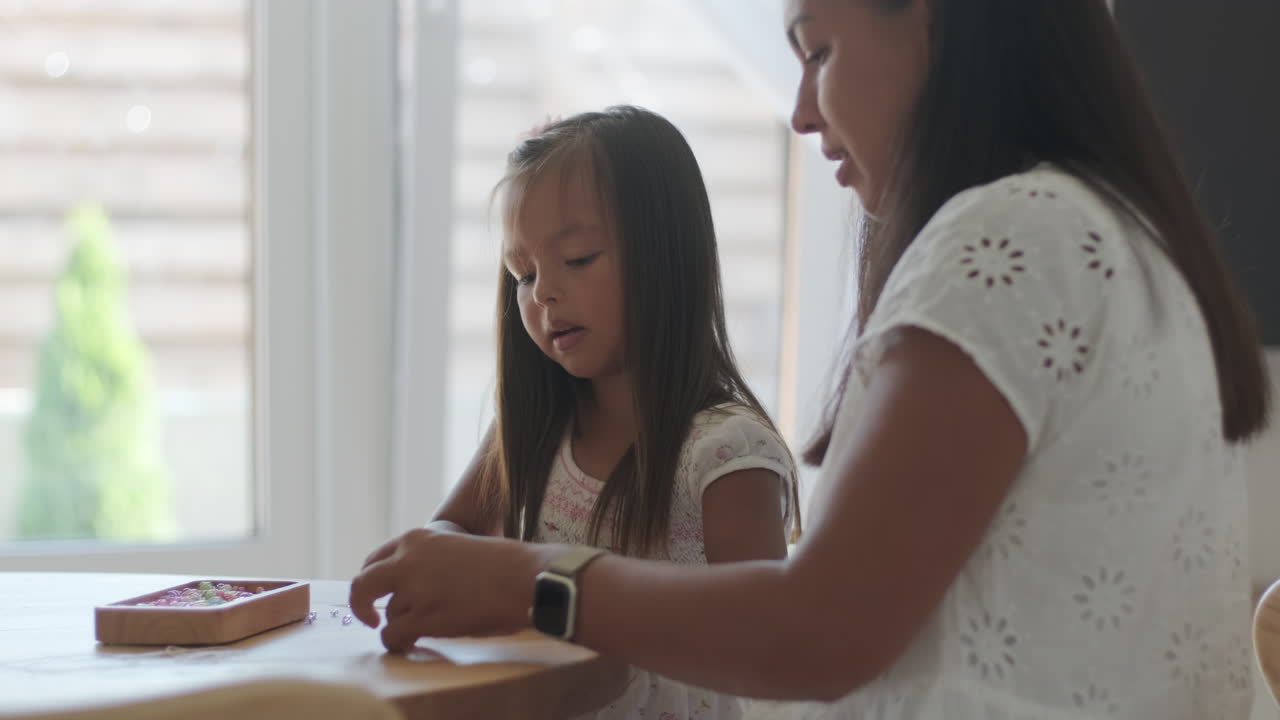 어머니와 딸이 함께 구슬을 고 있습니다.