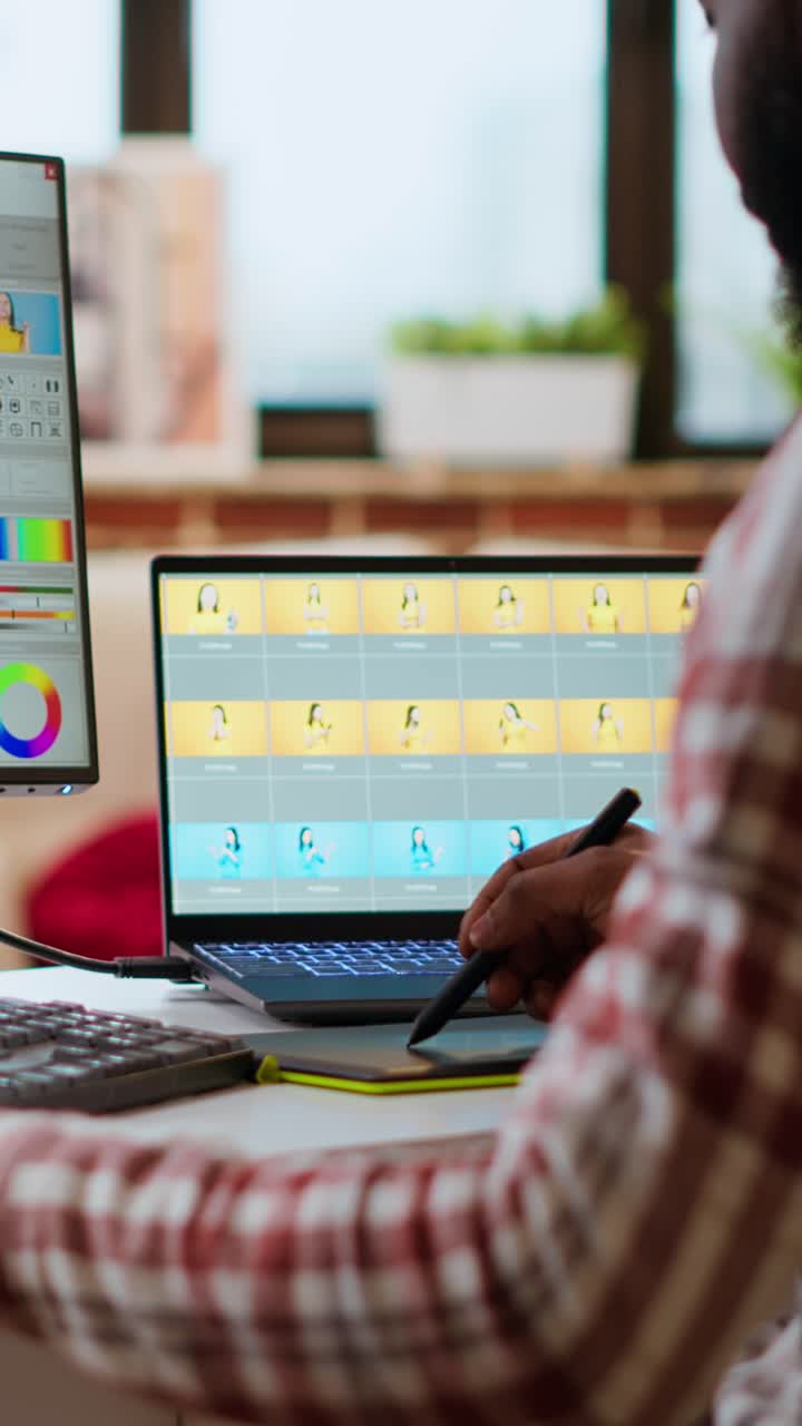 Vertical Video African american male designer edits images on dual monitors