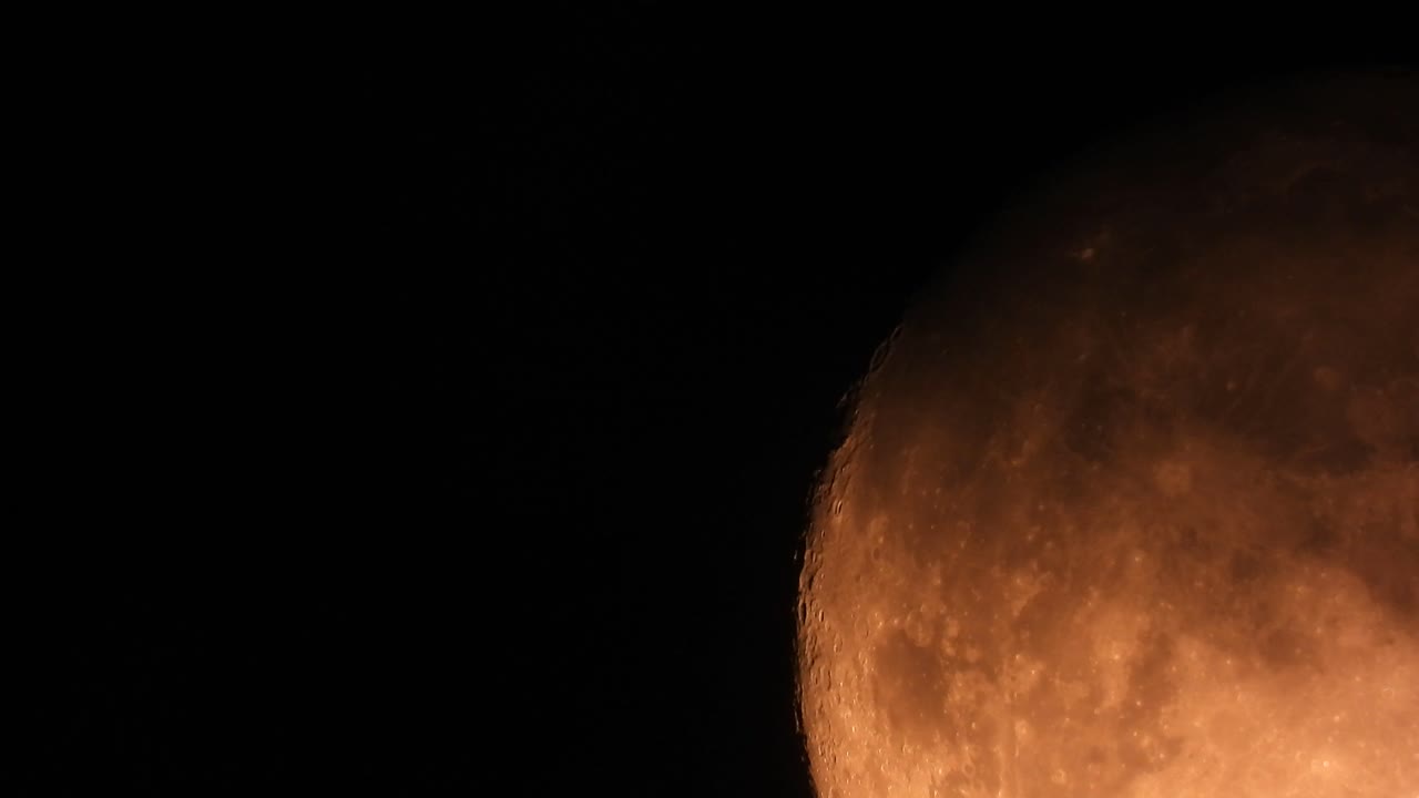 Extreme close-up shot of orange full moon in dark black sky