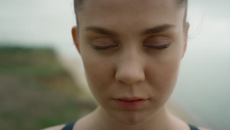 Calm-woman-opening-eyes-standing-on-beach-close-up.-Serious-girl-looking-camera