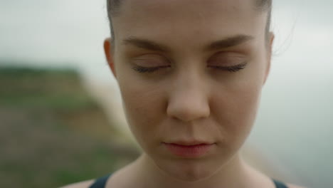mujer tranquila abriendo los ojos de pie en la playa de cerca. chica seria buscando cámara