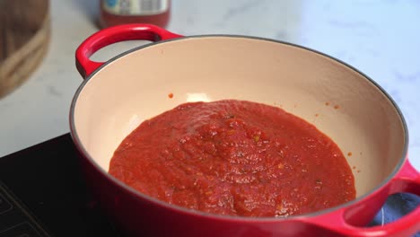 close up view of boiling tomato sauce in kitchen pot, steam rising during cooking process