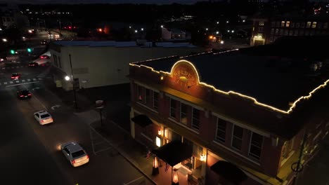 aerial approaching shot of traffic jam on street of american town. golden leaf bistro decorated on roof in winter season. night scene in small historic town. virginia, usa.