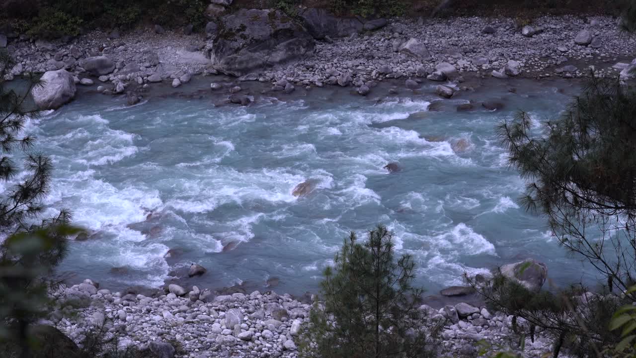 Una vista dall'alto di un fiume che scorre con acqua glaciale sui monti dell'Himalaya in Nepal.