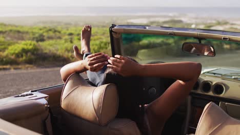 african american woman sitting with her feet on the window of convertible car