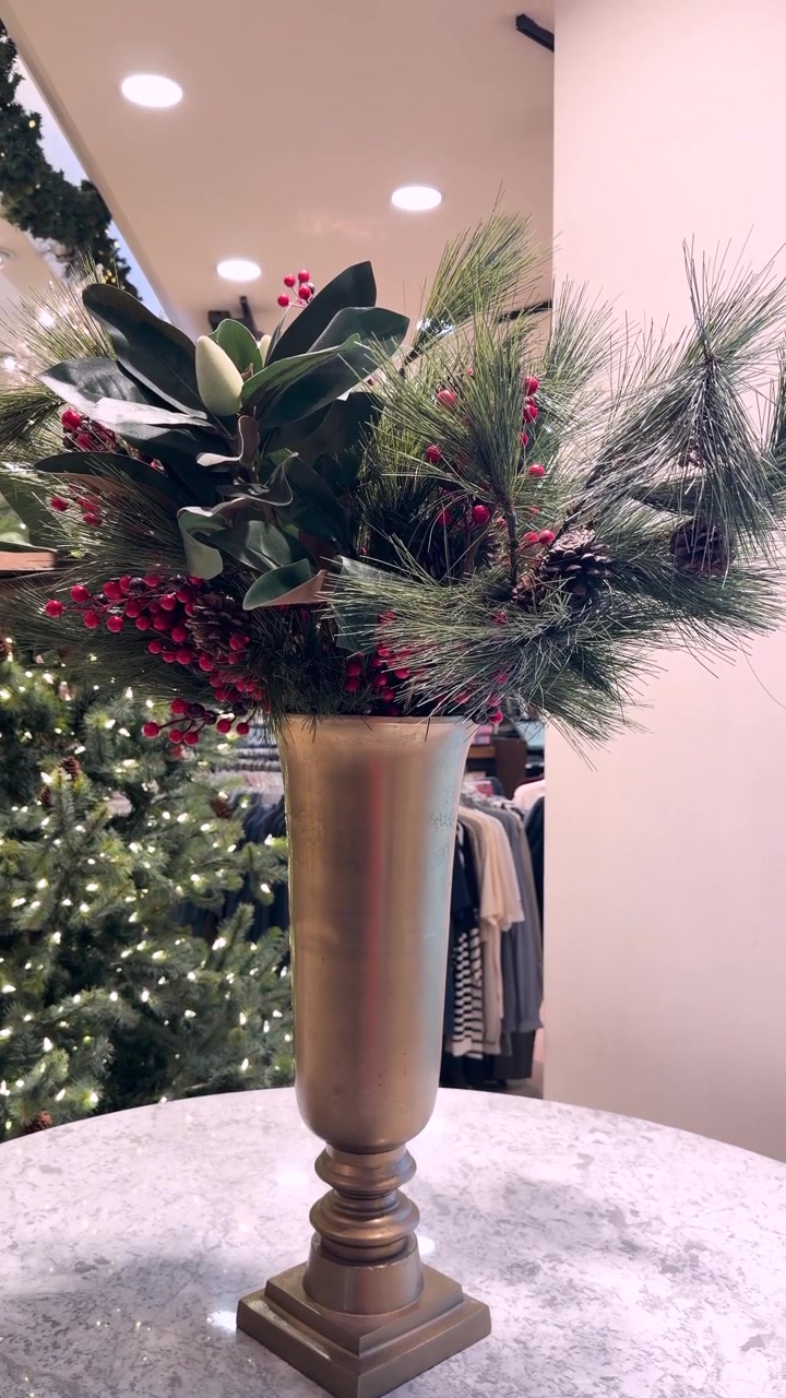 Festliches Arrangement aus Kiefernzweigen und Beeren in goldener Vase auf dem Tisch, Szene mit festlicher Innendekoration