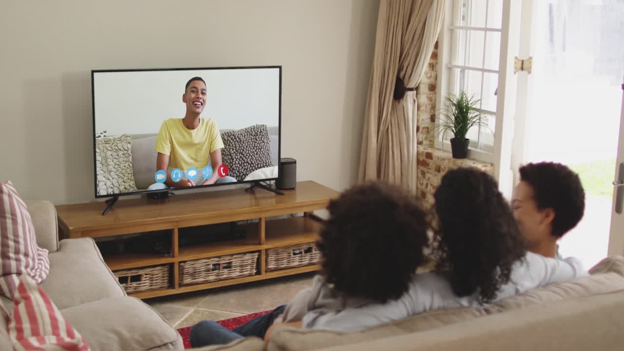 Famiglia afroamericana che fa una videochiamata in TV mentre è seduta sul divano a casa
