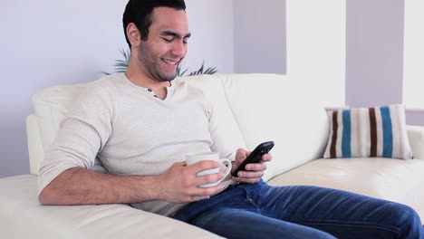 hombre guapo enviando un mensaje bebiendo café