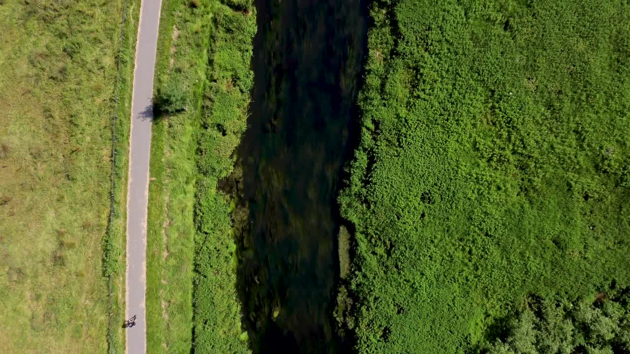 자전거 타는 사람이 경로를 타고 있는 캔터베리의 강 스투어 위로 날아가는 4k