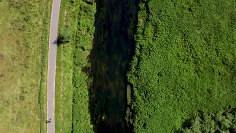 4k flying over the river stour in canterbury with a cyclist riding on the pathway