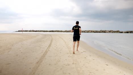 mature adult running alongside the edge of the ocean water, slow motion