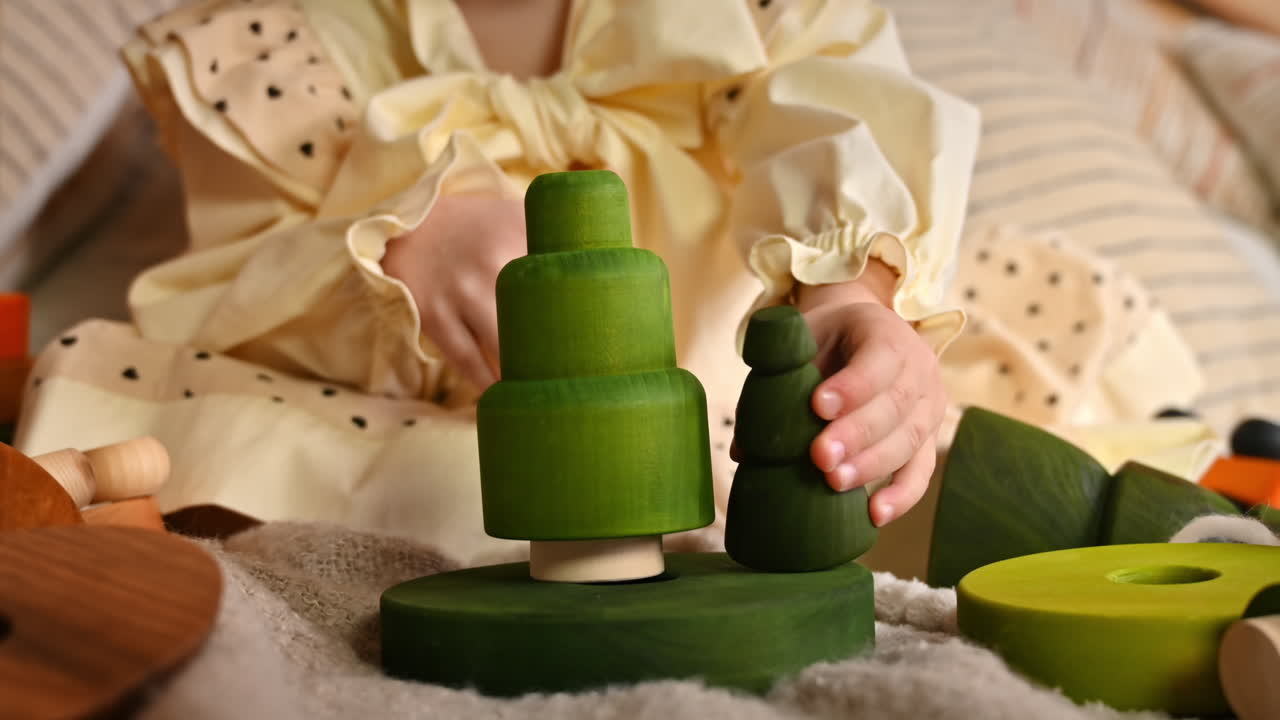 Little girl playing with several green wooden tree toys. Ecological and sustainability concept