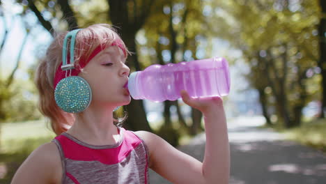 Athletic-fitness-sport-runner-child-girl-kid-drinking-water-from-bottle-after-training-exercising