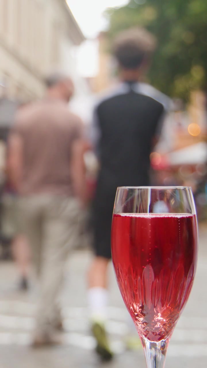 Bevanda rossa frizzante rinfrescante in un bicchiere da vino su una strada cittadina