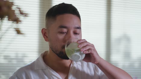 man drinking a green beverage