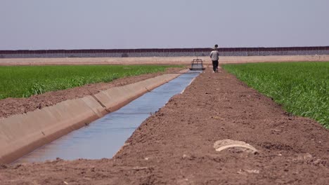 A-farmer-walks-along-the-US-Mexico-border-with-the-wall-in-the-background