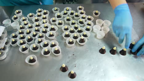 chocolate cone candies being put into individual paper. confectioners packaging sweet desserts. close up. top view.