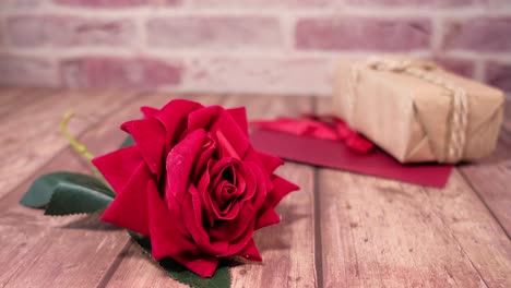 rosa roja y caja de regalos en una mesa de madera