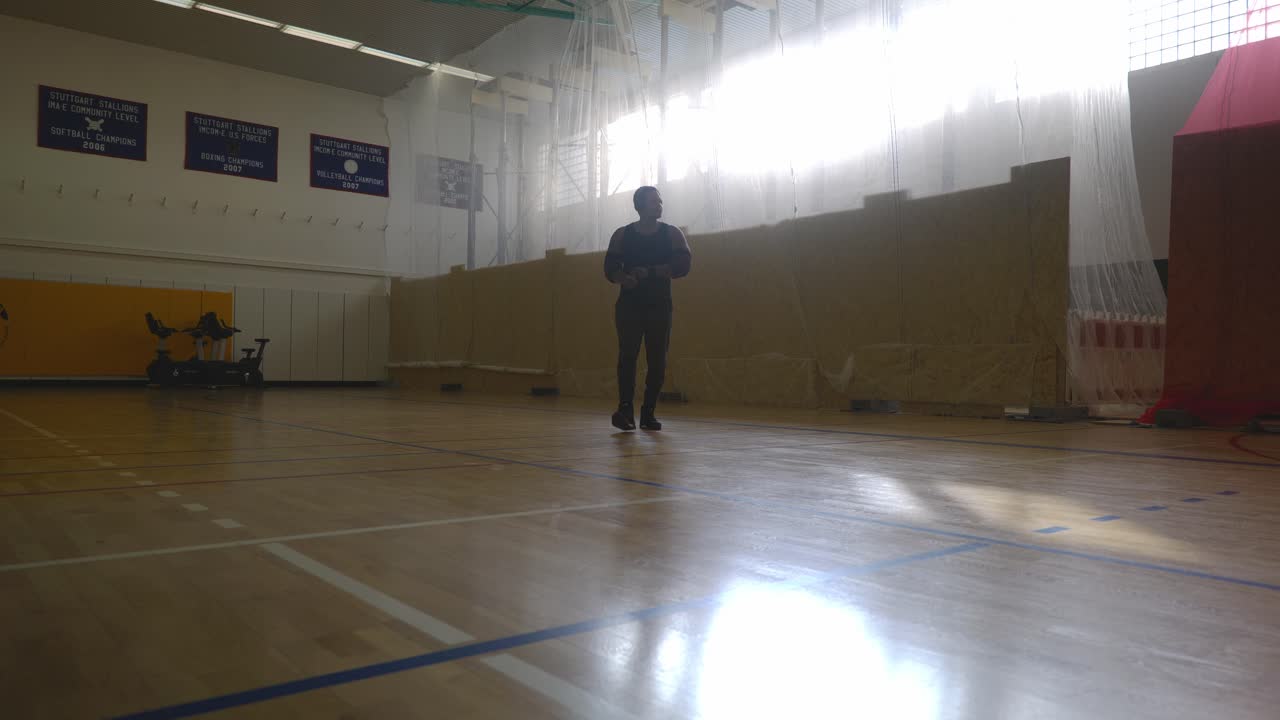 hombre frotándose las manos caminando desde la pared - hombre negro musculoso atlético fuerte parado en la cancha de baloncesto mirando alrededor en 4k