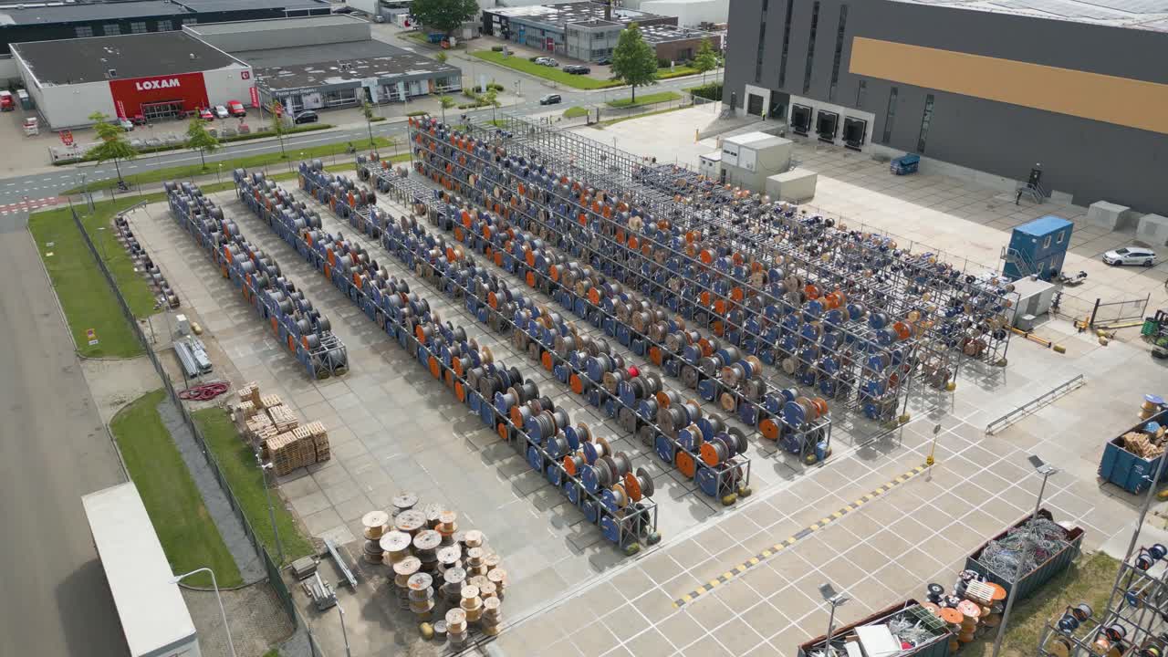 Aerial wide angle drone footage of an electrical cable storage yard outside an industrial building