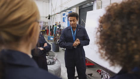 male tutor by whiteboard with students teaching auto mechanic apprenticeship at college