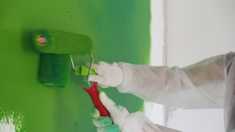 builders in protective suits paint wall green closeup