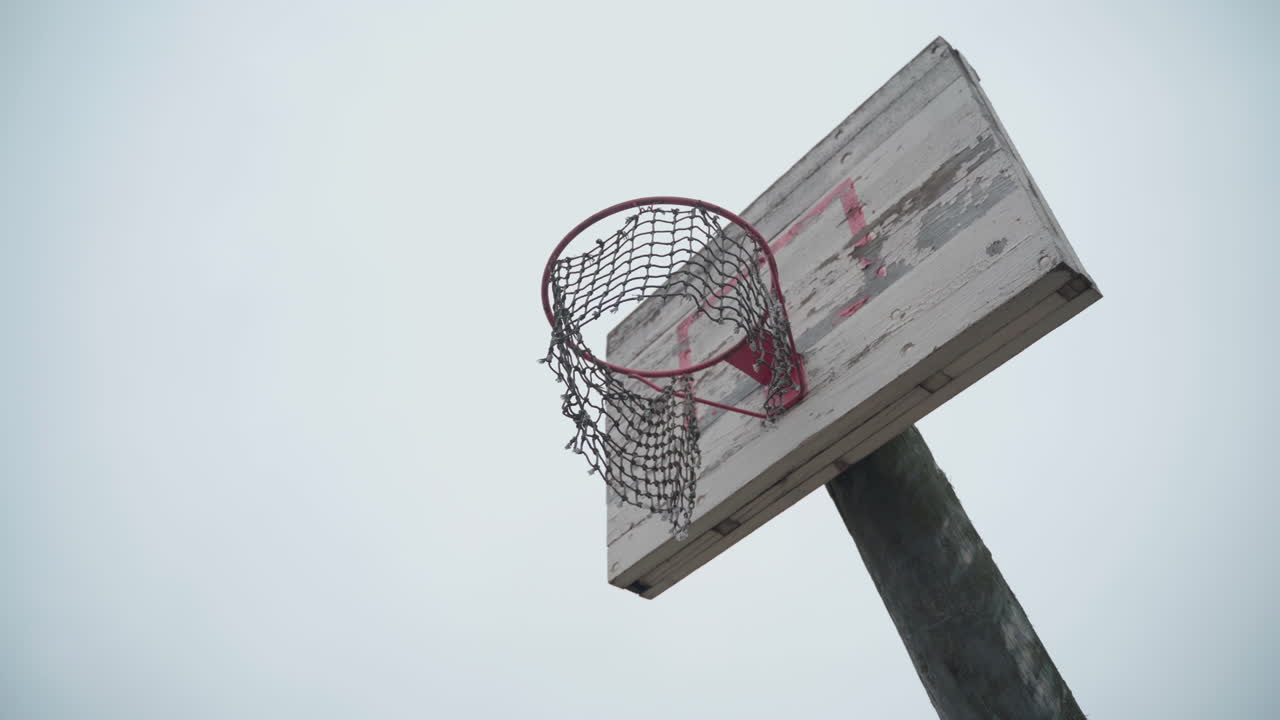 viejo aro de baloncesto con red rota colgando en el viento y pintura pelada