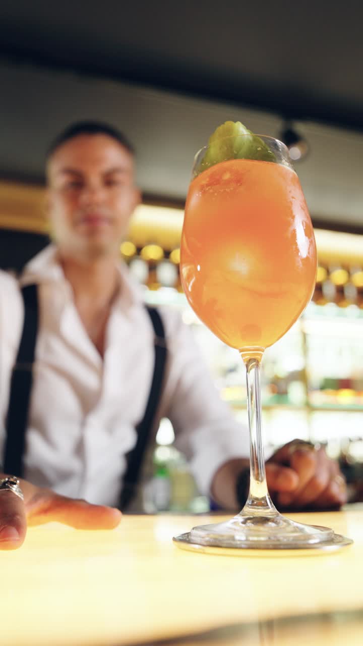 Barman sorridente presenta un rinfrescante cocktail all'arancia in un bar moderno