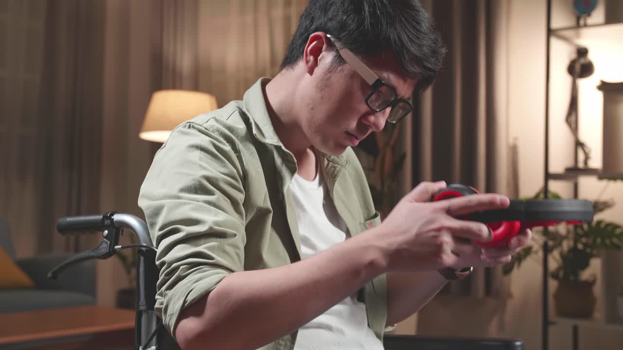 Asian Man Sitting In A Wheelchair Listening To Music With Headphones In Living Room