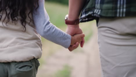 father and daughter holding hands walking outdoors