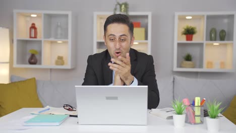 home office worker man applauding what he sees on laptop.