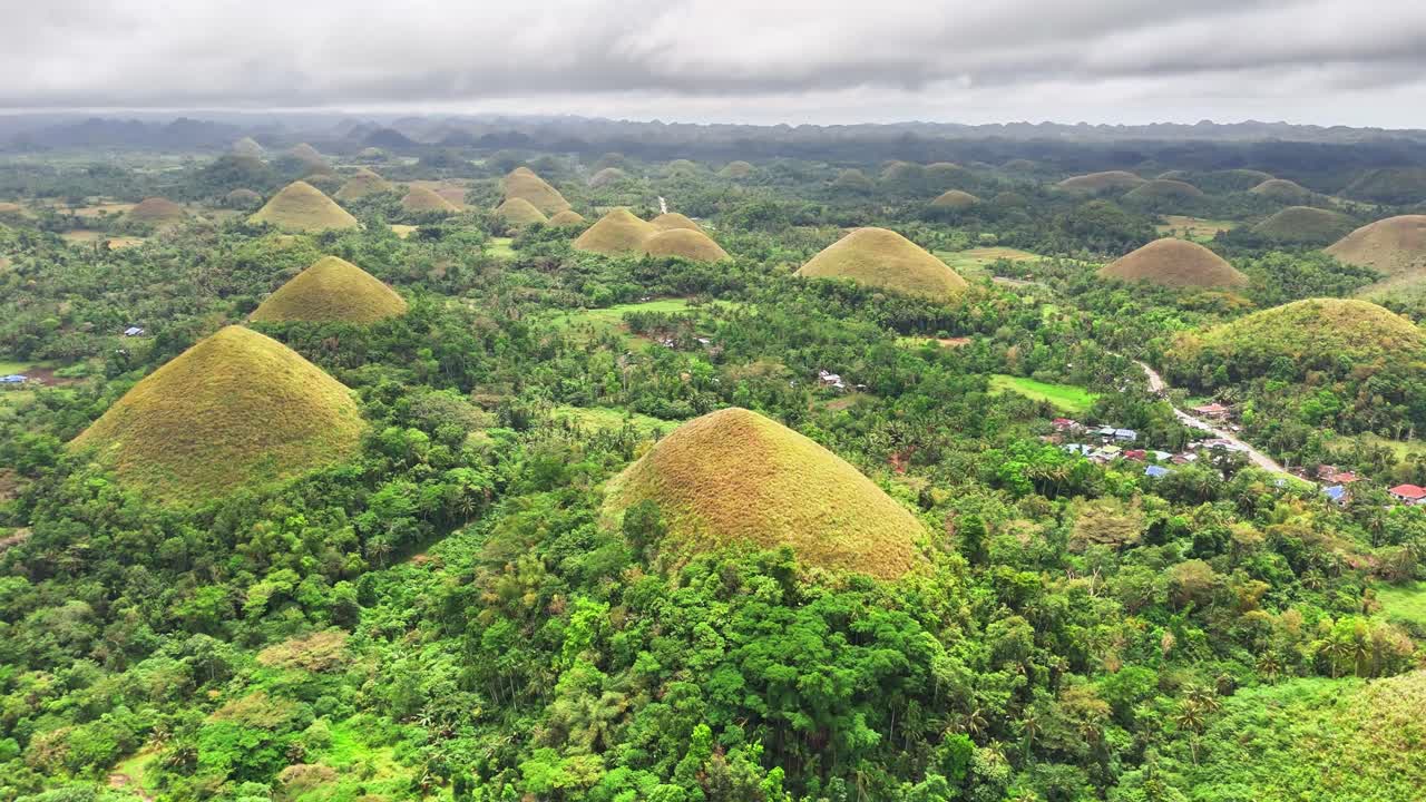 Drone slowly pulls back revealing the unique geological formations of the Chocolate Hills in Bohol, Philippines, a surreal tropical landscape of grassy conical hills covered in green vegetation