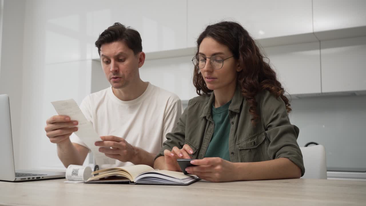 el marido y la esposa están sentados en la mesa de la cocina con una computadora portátil y calculando los gastos, formando un presupuesto familiar