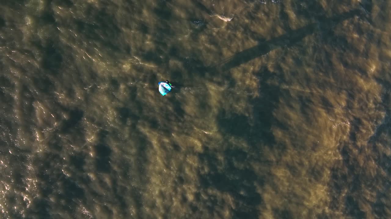 воздушный снимок сверху вниз виндсерфинга на коричневом северном море в солнечный день - трекинг кадр