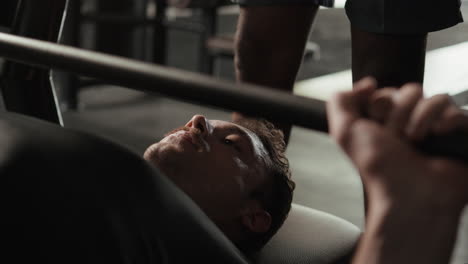 man performing bench press exercise with trainer