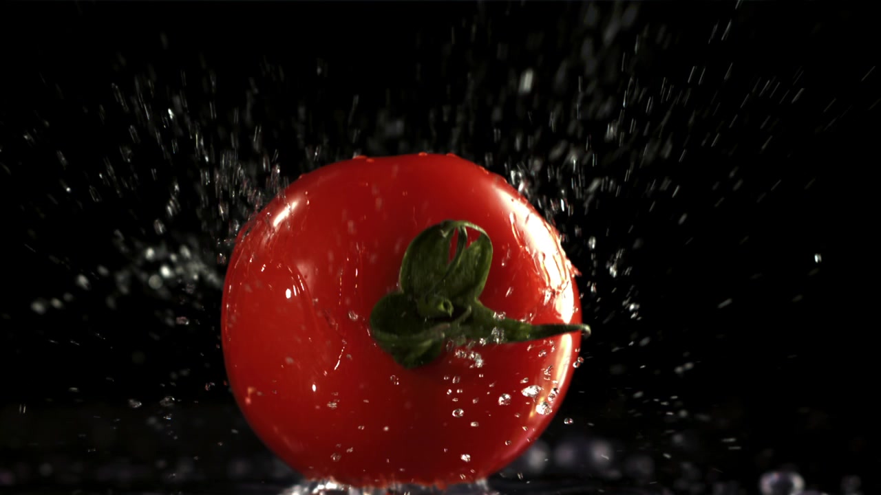 Ripresa al rallentatore di un pomodoro rosso che schizza nell'acqua