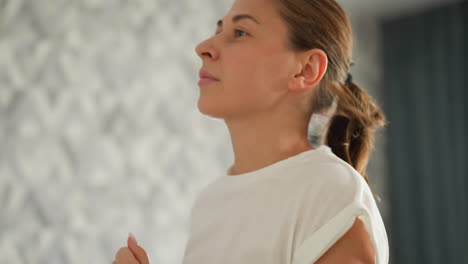 woman with waving ponytail runs on treadmill at home closeup. happy lady in enjoys jogging on machine trainer in domestic gym. positive activity