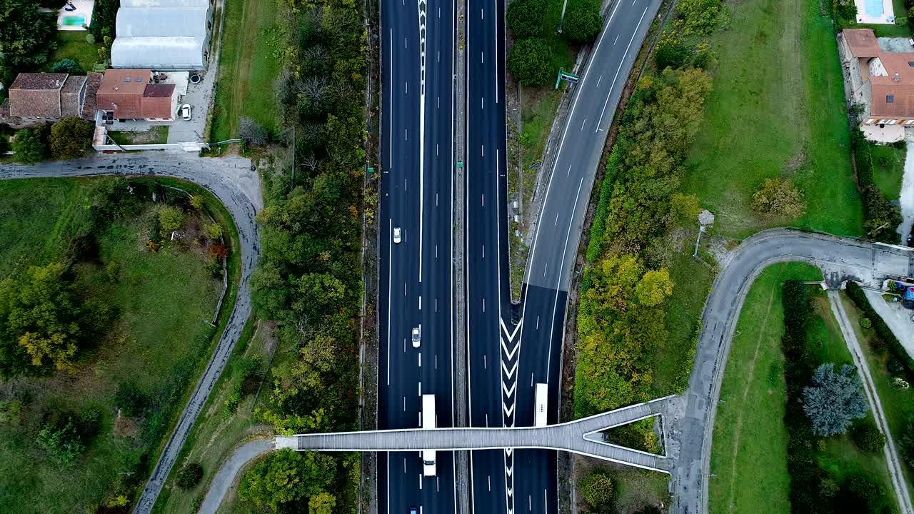 프랑스의 고속도로 교차로 위의 멋진 공중 풍경, 도로 주변의 집과 풀, 도로 다리 아래를 지나가는 자동차와 트럭.