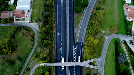 maravillosa vista aérea sobre el cruce de autopistas en francia sólo casas y campos de hierba alrededor de las carreteras coches y camiones que conducen por las carreteras que pasan por debajo de un puente de carretera
