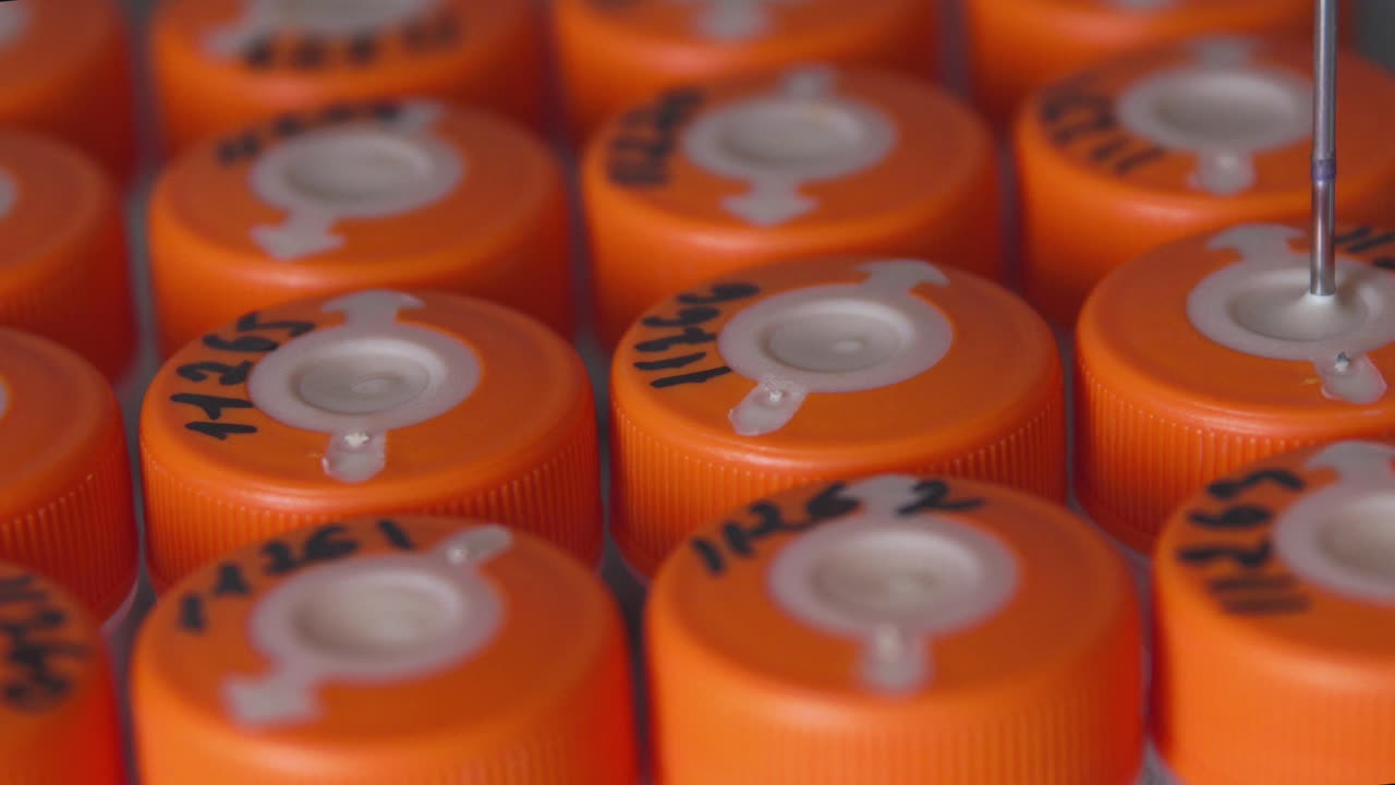 en el laboratorio médico, el robot perfora un frasco de líquido con una aguja y lo vierte en un tubo para que el médico lo analice más a fondo.