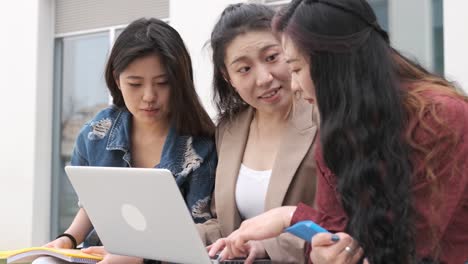 three asian girl students using the laptop at break time sitting on campus