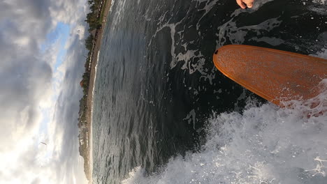 pov of person surfing on tropical ocean wave on a yellow foamboard