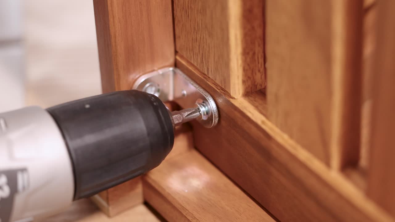 A power drill secures screws into wooden furniture, highlighting efficient assembly in a well-lit environment
