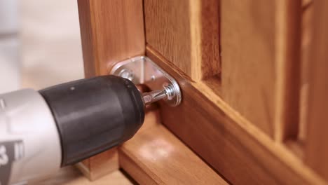 a power drill secures screws into wooden furniture, highlighting efficient assembly in a well-lit environment